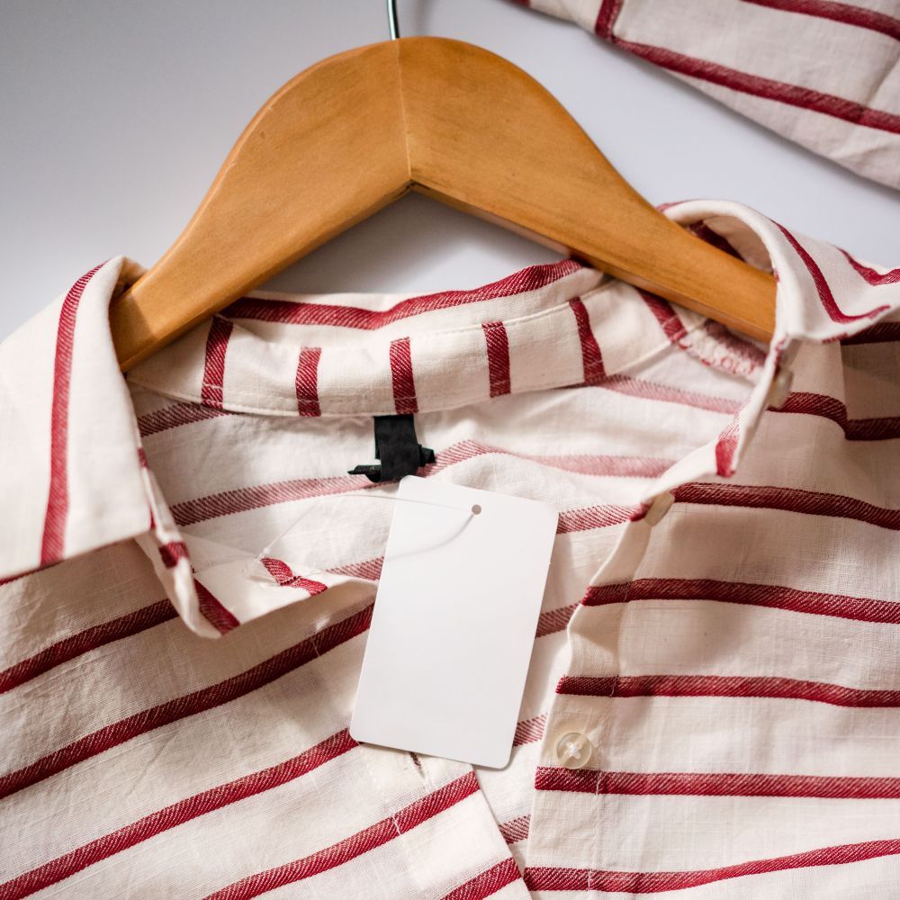 Striped shirt on a wooden hanger with a blank printed hang tag and woven neck label
