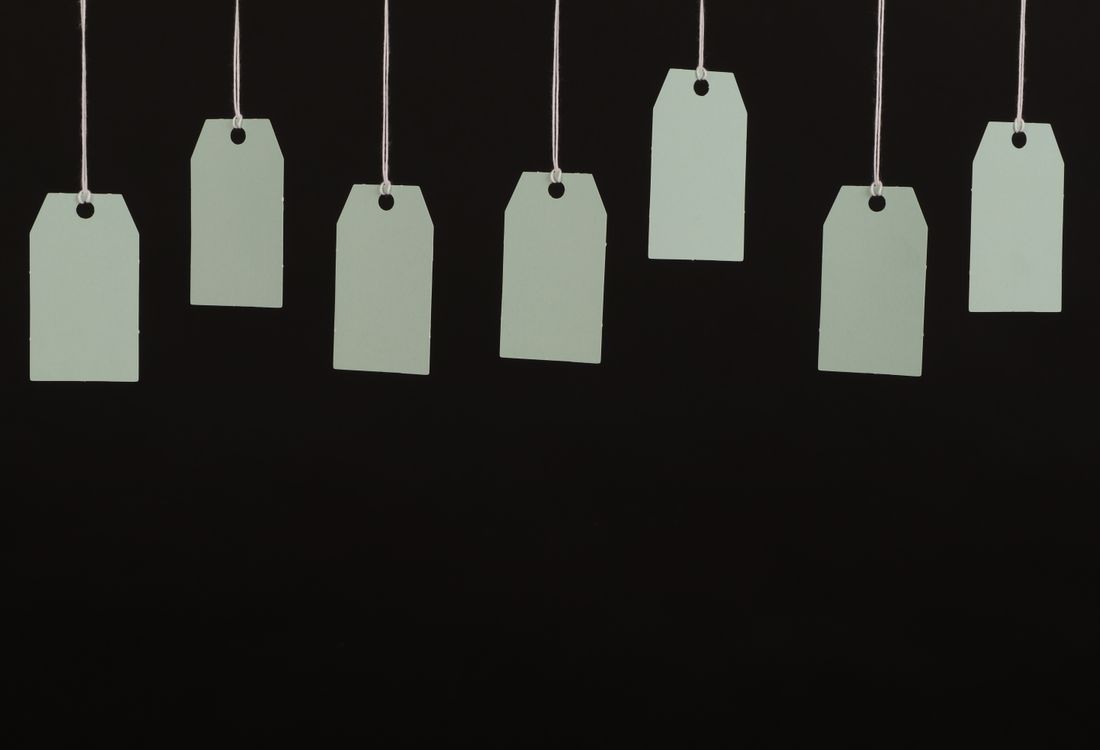 Stack of blank die-cut cardboard hang tags waiting for an approved print specification